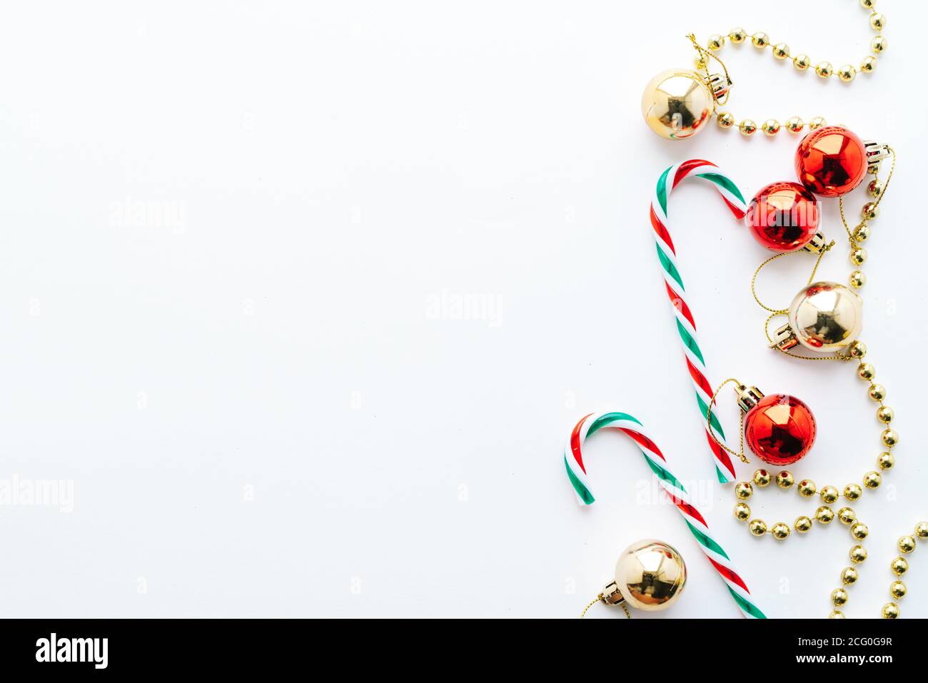 Cadre de Noël. Boules de Noël, guirlande, décorations rouges et dorées, bonbons de noël sur fond blanc. Flat lay, vue de dessus, espace de copie Banque D'Images