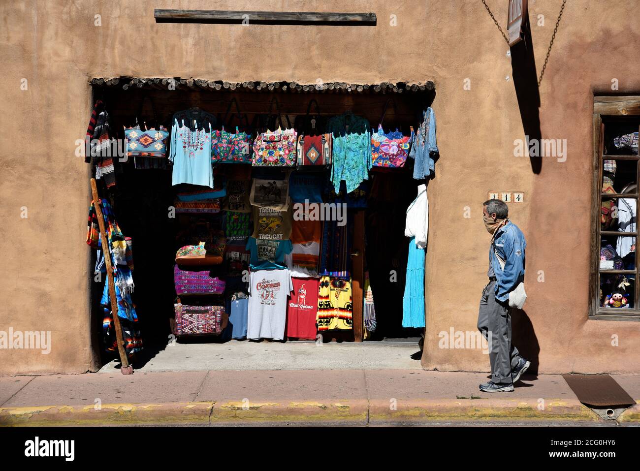 Un homme portant un masque pandémique passe devant une boutique de souvenirs et de vêtements à Santa Fe, au Mexique. Banque D'Images