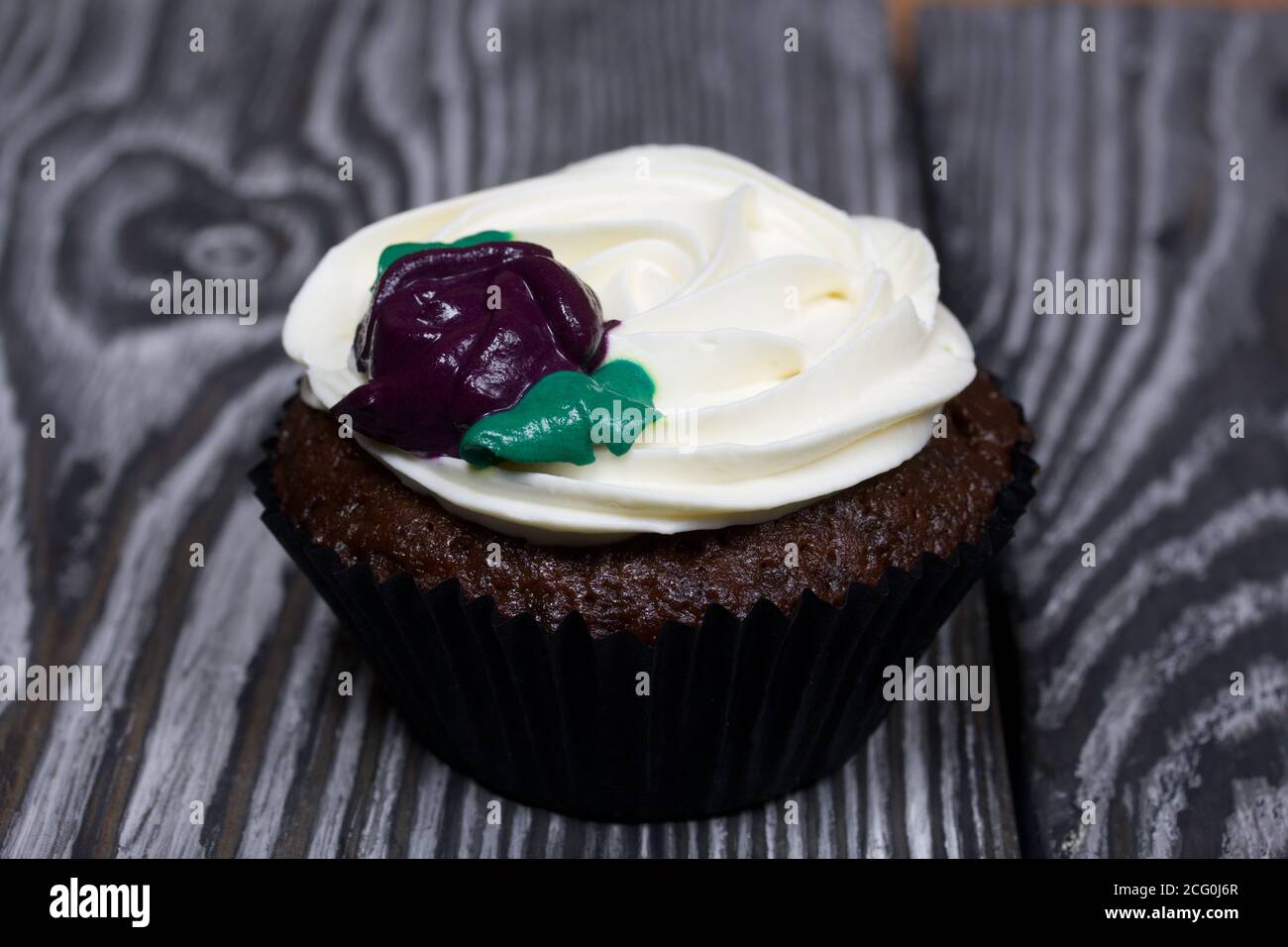 Muffins au chocolat avec fleur de crème. Elle repose sur des planches de pin peintes en noir et blanc. Banque D'Images