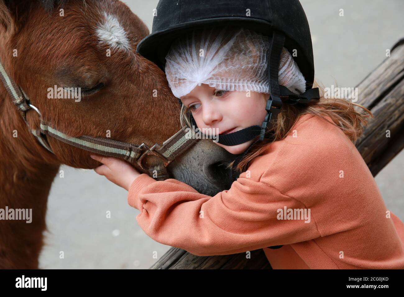 Petite fille qui câlin un poney aux écuries, France Banque D'Images