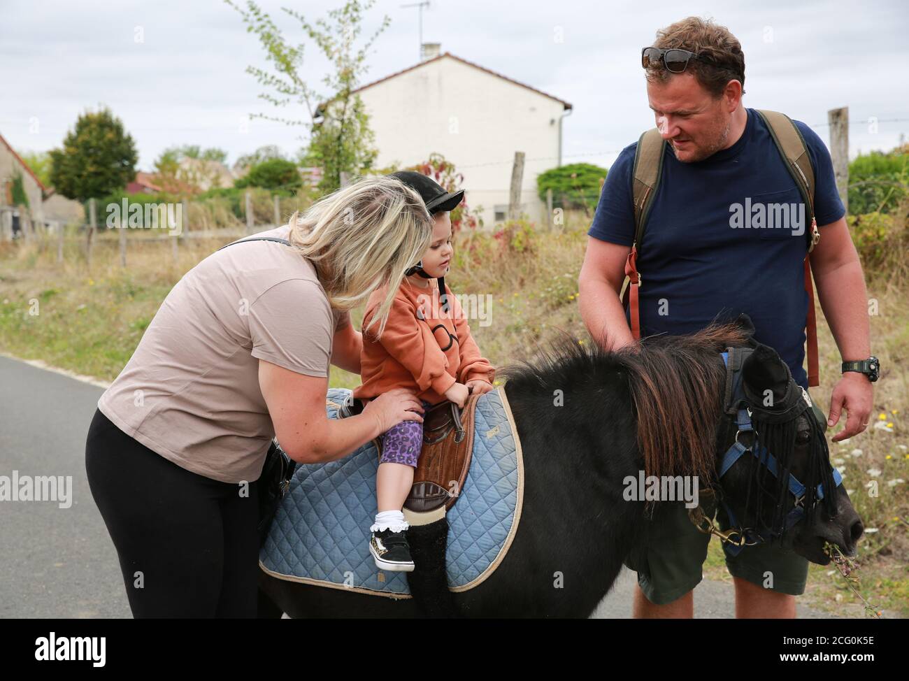 Petite fille poney à cheval dans une écurie avec ses parents, France Banque D'Images