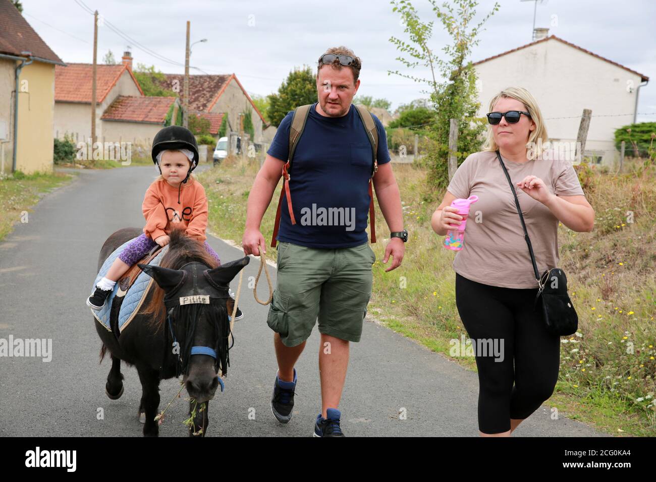 Petite fille poney à cheval dans une écurie avec ses parents, France Banque D'Images