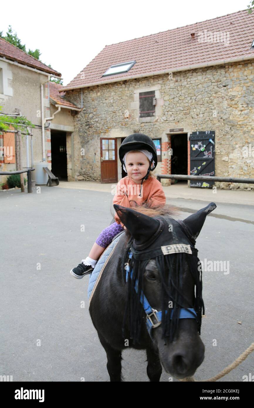 Petite fille poney à cheval dans une écurie, France Banque D'Images