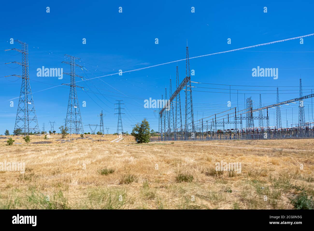 Vue de la centrale électrique haute tension et des tours de traversée de câble haute tension dans un champ d'herbe verte... Banque D'Images