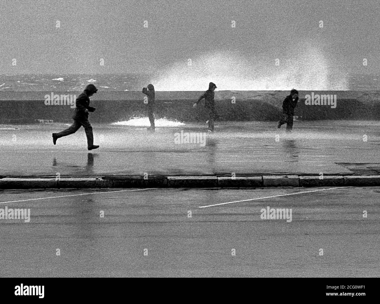 AJAXNETPHOTO. 1975. SOUTHSEA, ANGLETERRE. - SPRAY DODGERS - LES JEUNES ESQUIVENT LE JET COMME LES MERS CRASH AU-DESSUS DE LA PARAPIT LE LONG DE CLARENCE ESPLANADE PENDANT UN AUTOMNE GALE.PHOTO:JONATHAN EASTLAND/AJAX REF:75046 5 60 Banque D'Images