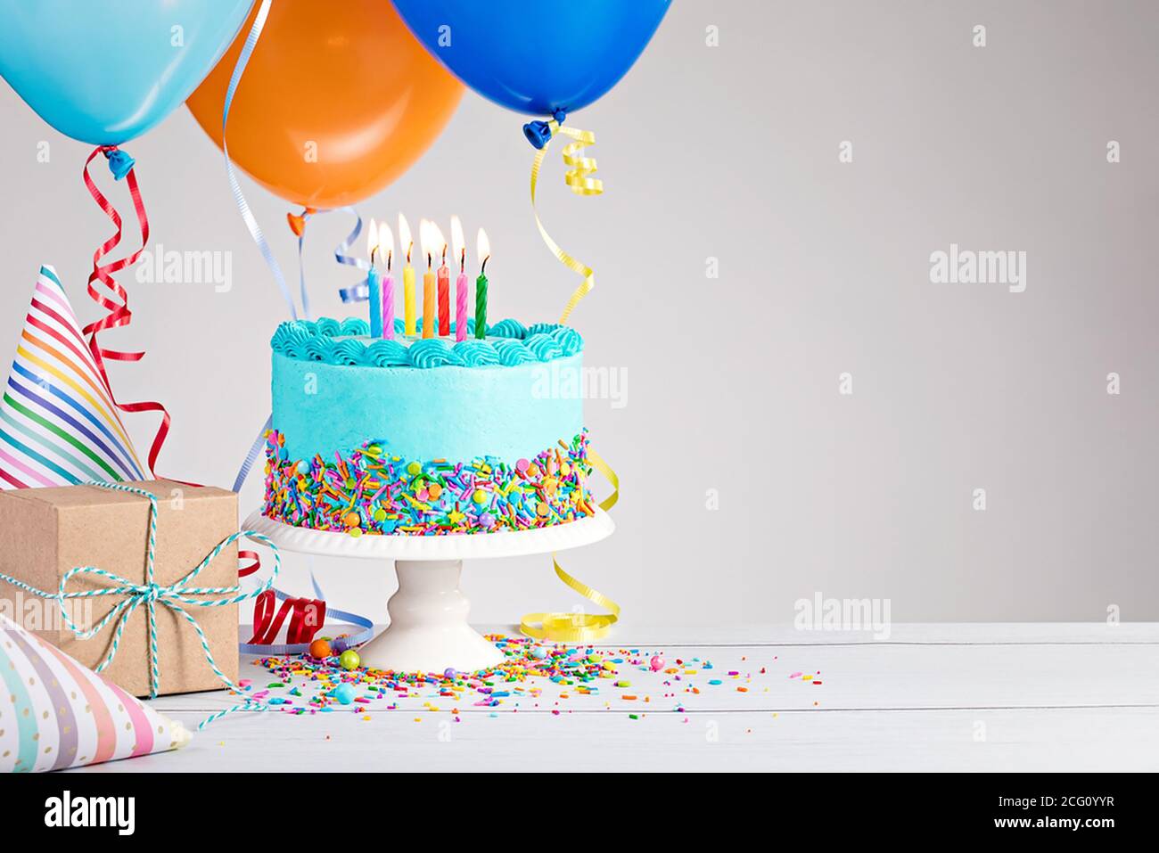 Gâteau d'anniversaire bleu, cadeaux, chapeaux et ballons colorés sur le gr  clair Photo Stock - Alamy