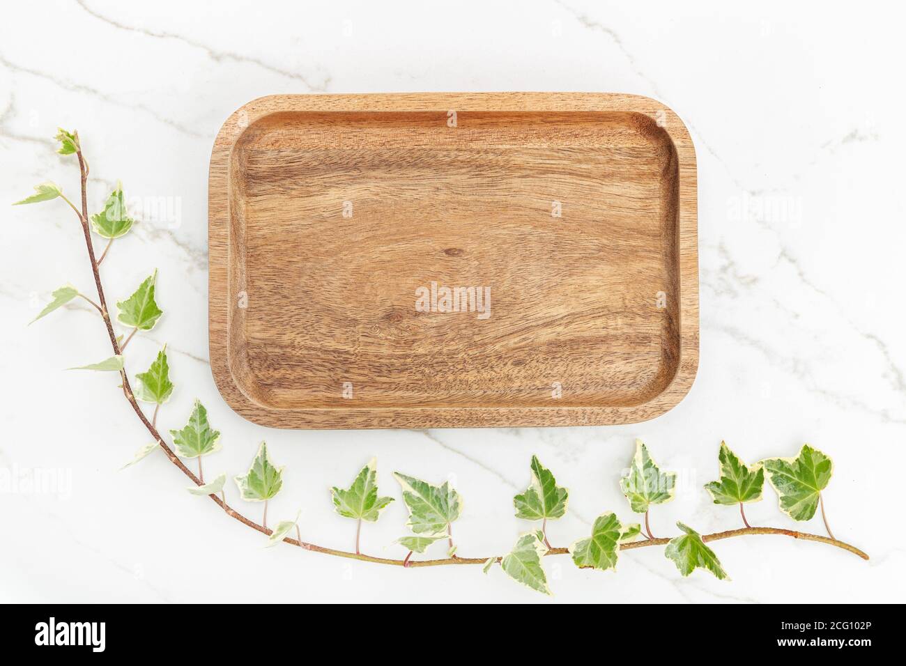 Plateau plat en bois et feuilles de lierre verte sur fond de marbre blanc. Maquette Banque D'Images