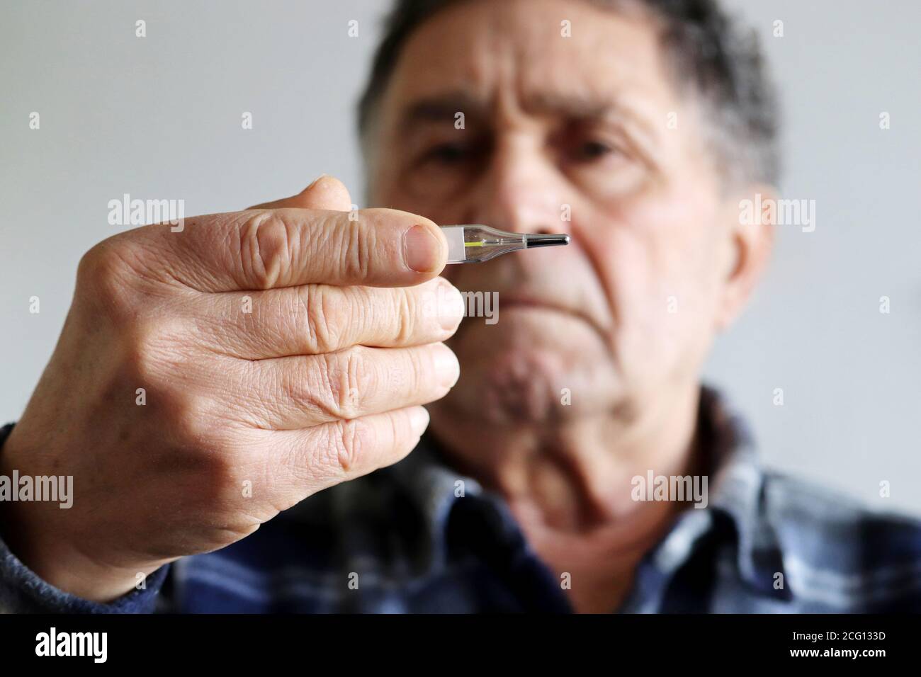 Homme âgé mesurant la température corporelle avec thermomètre au mercure. Concept de fièvre, traitement froid, symptômes du coronavirus Banque D'Images