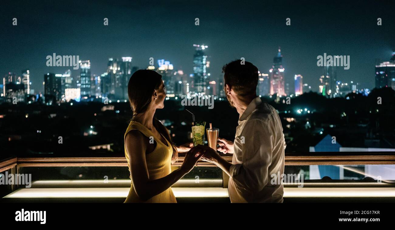 Couple prenant un verre sur la terrasse du toit donnant sur la ville Banque D'Images