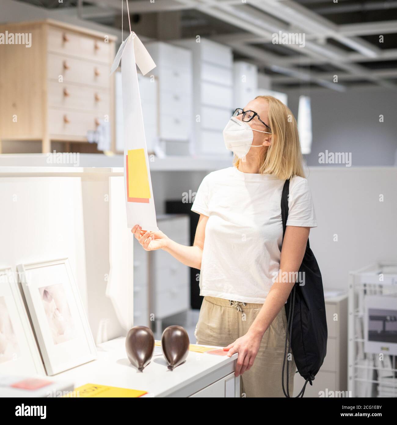 Nouvelle normale pendant l'épidémie de covid. Femme caucasienne magasiner au magasin de meubles et d'accessoires à la maison portant masque médical de protection pour le visage Banque D'Images