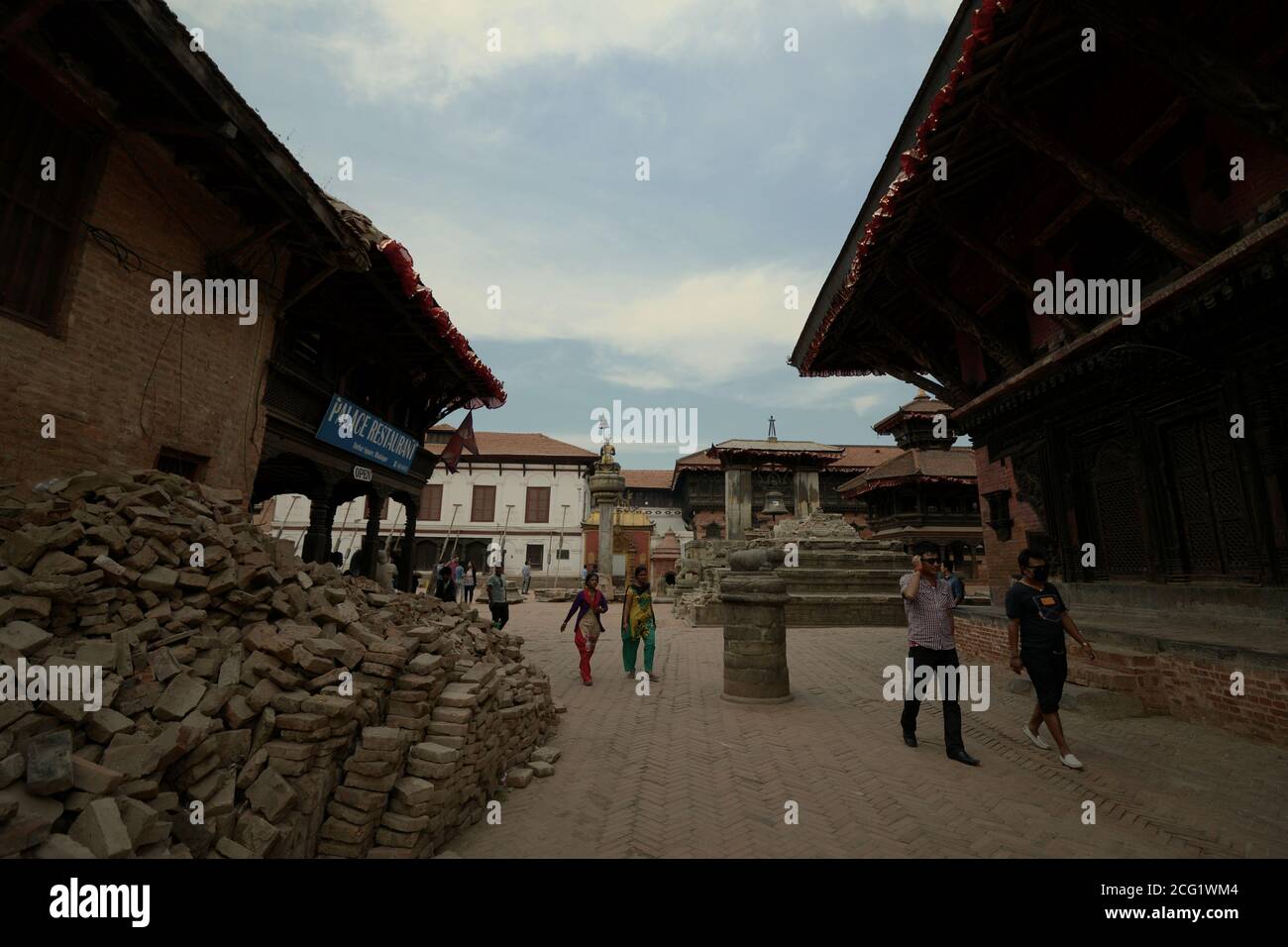 Citoyens et touristes marchant à travers un passage entre deux bâtiments sur la place historique Durbar de Bhaktapur, Népal. Banque D'Images Citoyens et touristes marchant à travers un passage entre deux bâtiments sur la place historique Durbar de Bhaktapur, Népal. Banque D'Images
