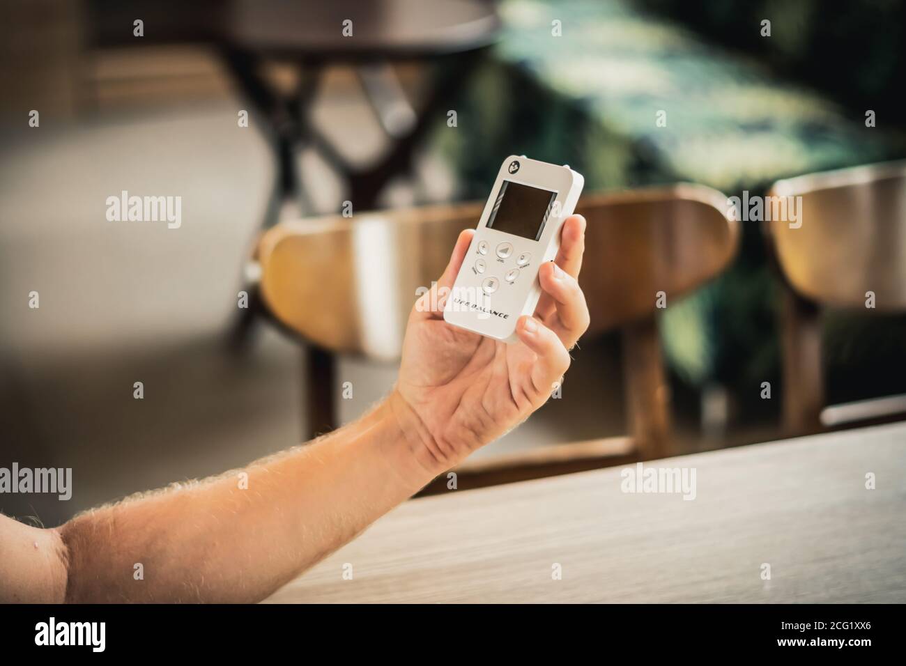 Jeune homme main tenir bio rezonans thérapie dispositif de médecine alternative, petit portable équilibre de vie bioresonance pour le traitement maladies de l'appareil circulatoire Banque D'Images