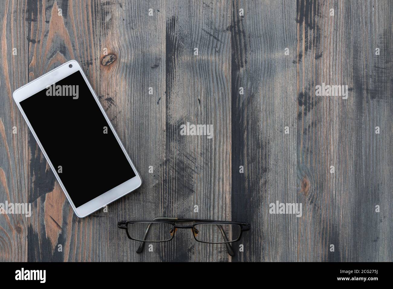 Smartphone mobile avec écran noir et vieilles lunettes sur fond en bois de style vintage. Flat lay, espace de copie Banque D'Images