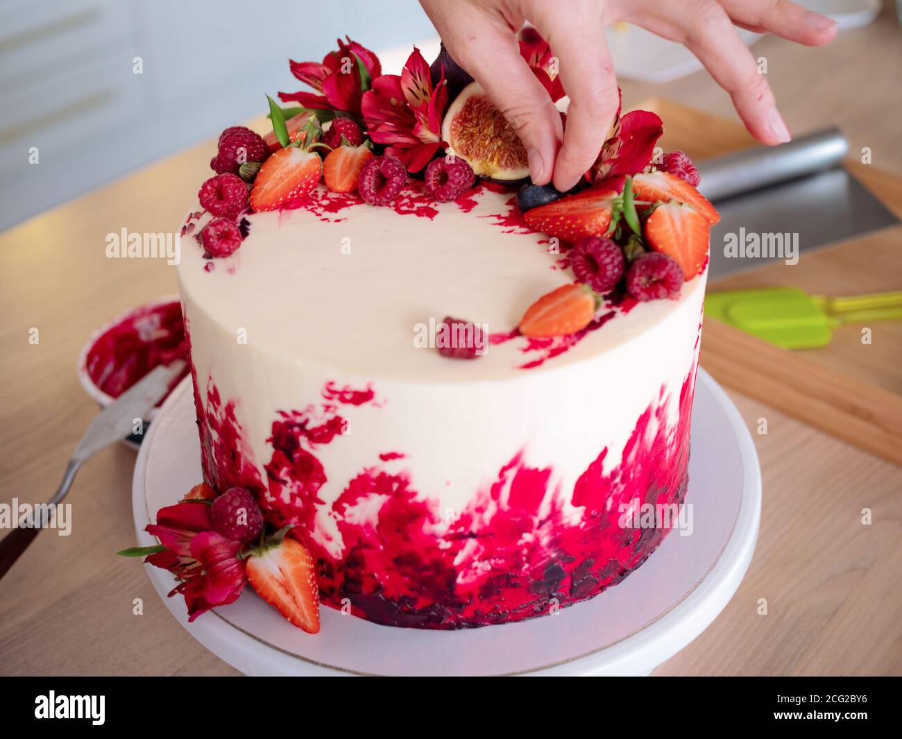 Cuisson Et Decoration De Gateau A La Creme Jeune Femme Chef Patissier Dans La Cuisine Decorant Gateau De Velours Rouge Avec Des Fleurs Et Des Baies Photo Stock Alamy