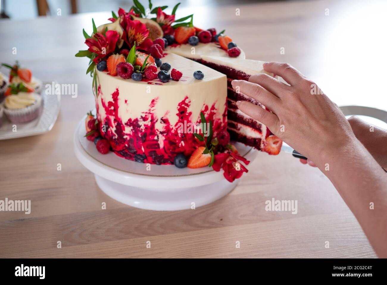 Grand Beau Gateau De Velours Rouge Avec Fleurs Et Baies Sur Le Dessus Coupez Une Partie Les Mains Des Femmes En Gros Plan Photo Stock Alamy