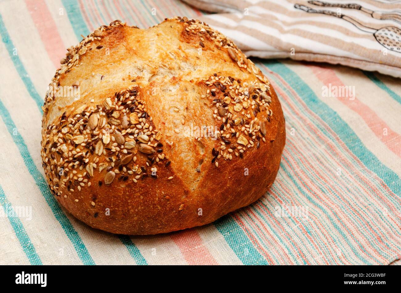 Pain de grain entier fraîchement cuit, parsemé de graines de lin, de sésame, de graines de tournesol sur une serviette en lin. Concept de saine alimentation. Cuisson à domicile Banque D'Images