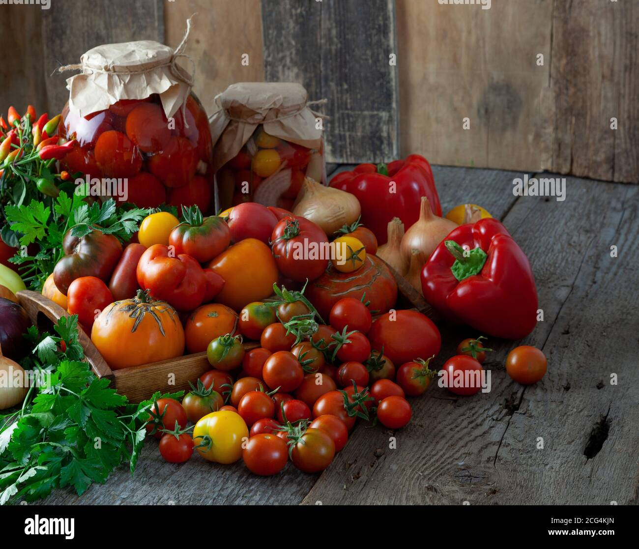 Tomates, poivrons, oignons sur la table. Préservation de la récolte automnale des légumes. Pot en verre avec tomates marinées. Arrière-plan en bois Banque D'Images