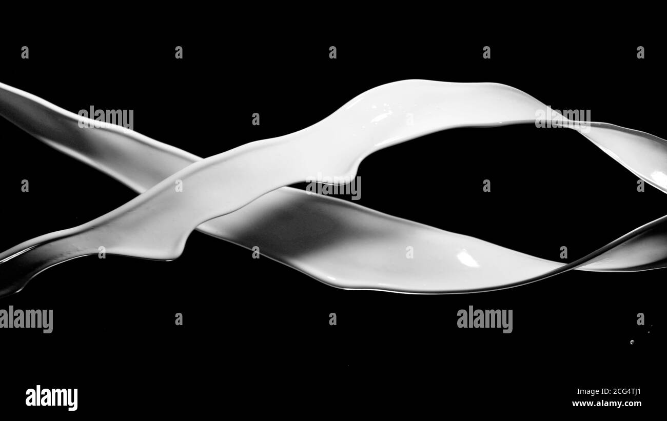 Éclaboussures de lait isolées sur fond noir. Forme abstraite en rotation. Banque D'Images