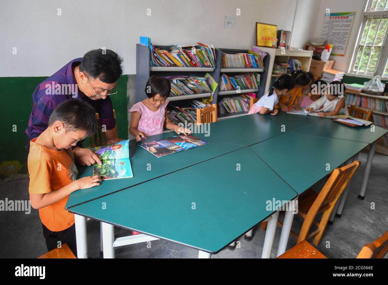 (200909) -- CHANGSHA, le 9 septembre 2020 (Xinhua) -- Dong Zhuwen (2e L) aide les élèves à lire des livres à l'école primaire de Chagan, dans le canton de Huju, comté de Chaling, dans la province de Hunan, au centre de la Chine, le 8 septembre 2020. Dong Zhuwen, 63 ans, est enseignant aux élèves de première et de deuxième année de l'école primaire de Chagan. Né dans le canton de Huju, Dong Zhuwen a commencé sa carrière d'enseignant ici en 1977. Après sa retraite en 2017, il a choisi de rester à l'école et de poursuivre l'enseignement, car l'école manquait d'enseignants. « J'aime les enfants, je veux rester pour eux », a déclaré Dong. Il espère également que de plus en plus de jeunes enseignants s'en médoussent Banque D'Images