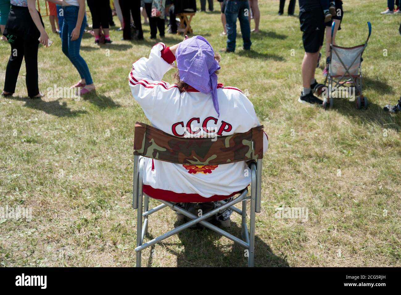 Une femme âgée dans une combinaison avec l'inscription URSS est assis sur une chaise pliante dans un dégagement contre La toile de fond des gens au Caratag mu Banque D'Images