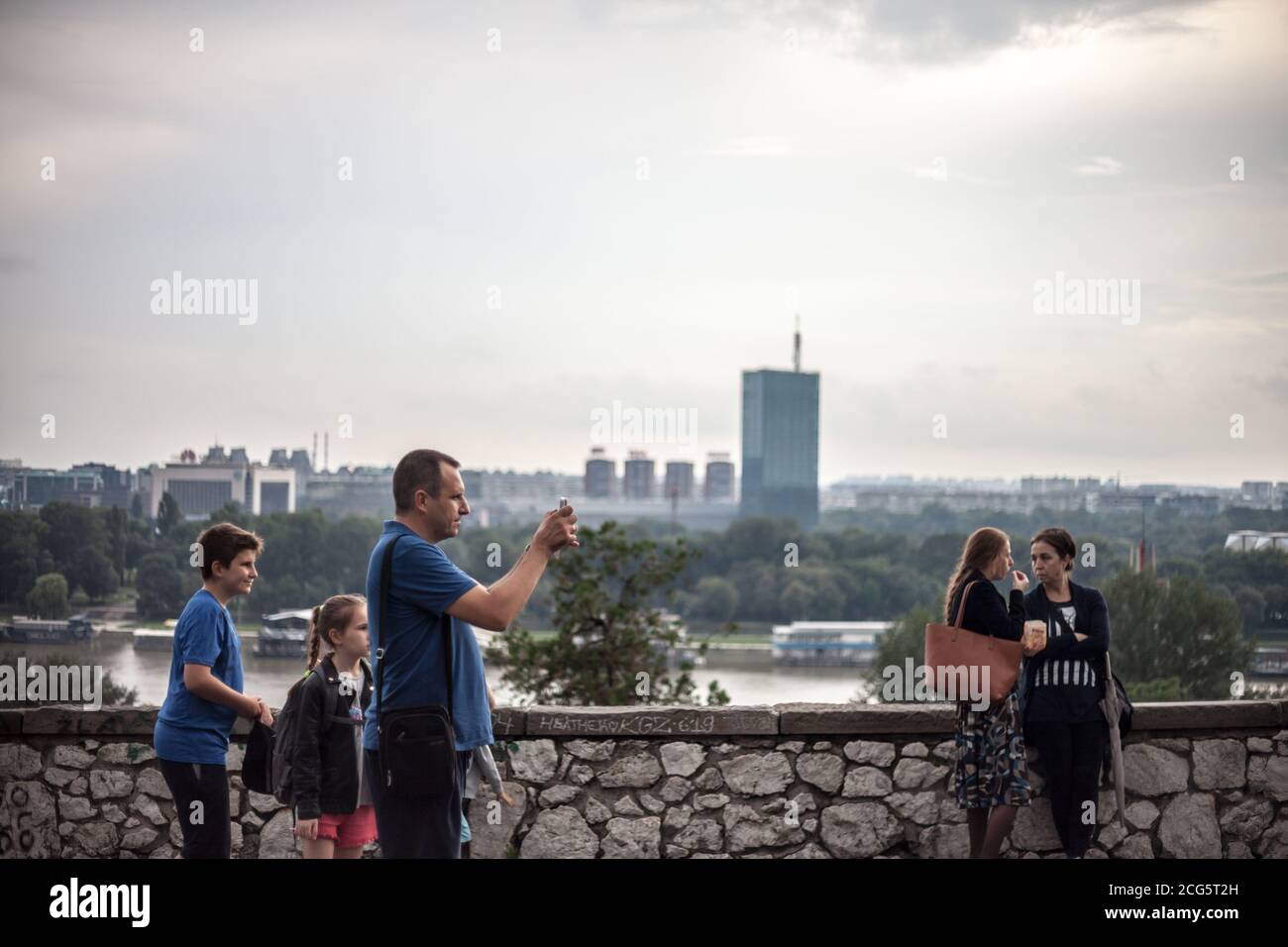 BELGRADE, SERBIE - 7 JUILLET 2018: Groupe de touristes prenant des photos et posant dans le parc de la forteresse de Kalemegdan avec un panorama des gratte-ciels et s. Banque D'Images