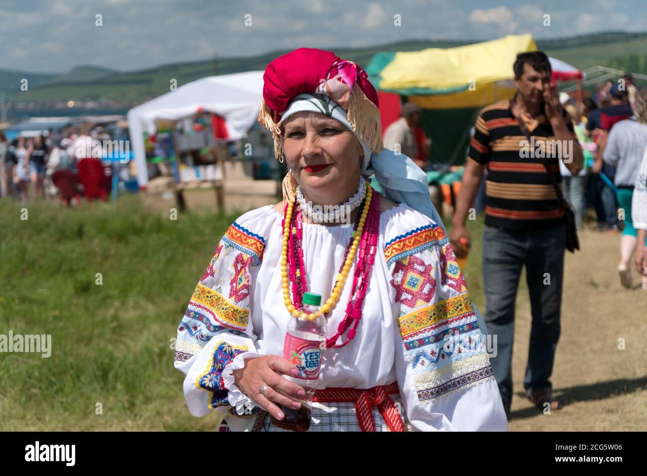 Une femme en costume folklorique russe marchant dans la rue pendant le  festival ethnique Caratag sur la rive d'un grand lac Photo Stock - Alamy