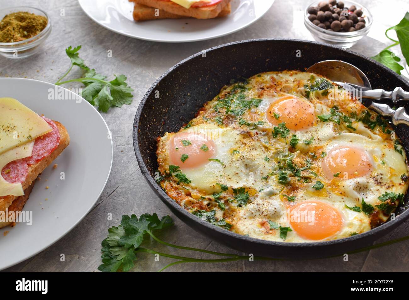 oeufs frits avec tomates, oignons et persil dans une casserole. Toast au fromage et à la saucisse. Petit déjeuner savoureux. Arrière-plan clair. Shakshuka. Banque D'Images