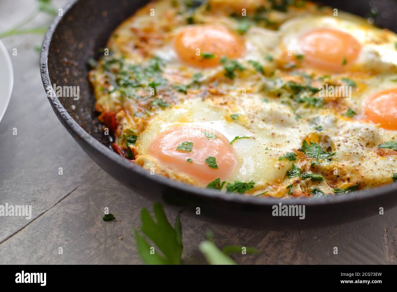 oeufs frits avec tomates, oignons et persil dans une casserole. Petit déjeuner savoureux. Arrière-plan clair. Shakshuka. Banque D'Images