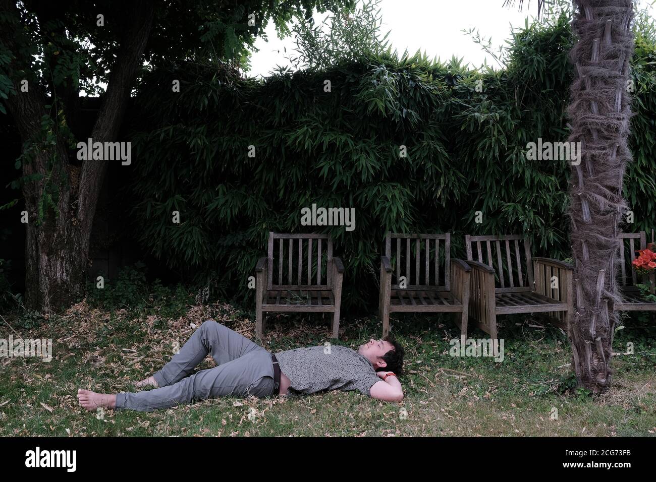 Homme couché sur l'herbe dans un jardin, France Banque D'Images