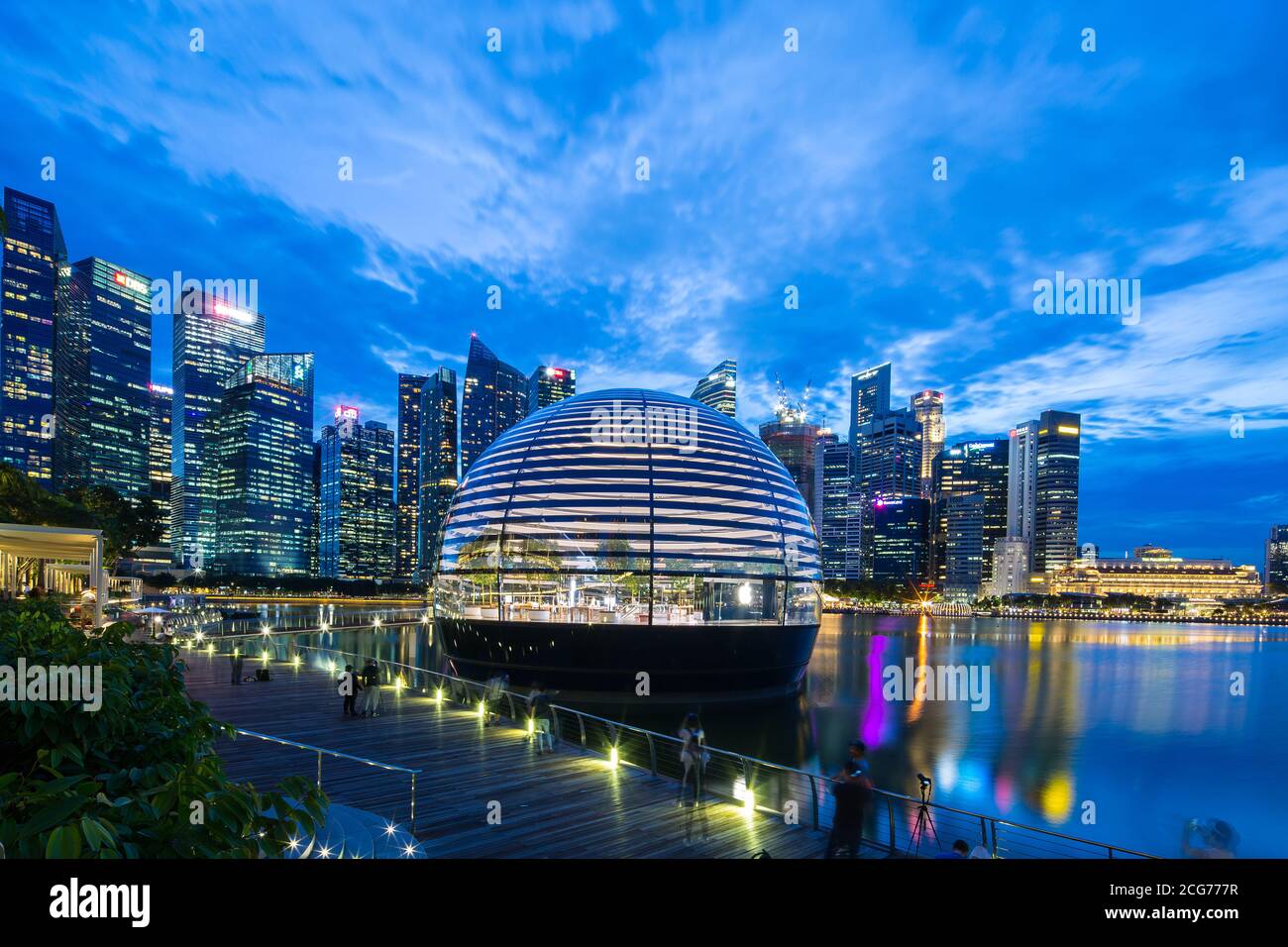 L'intérieur flottant de l'Apple Store est lumineux et dévoile au public, contre les gratte-ciel commerciaux de la ville comme arrière-plan, Singapour. Banque D'Images