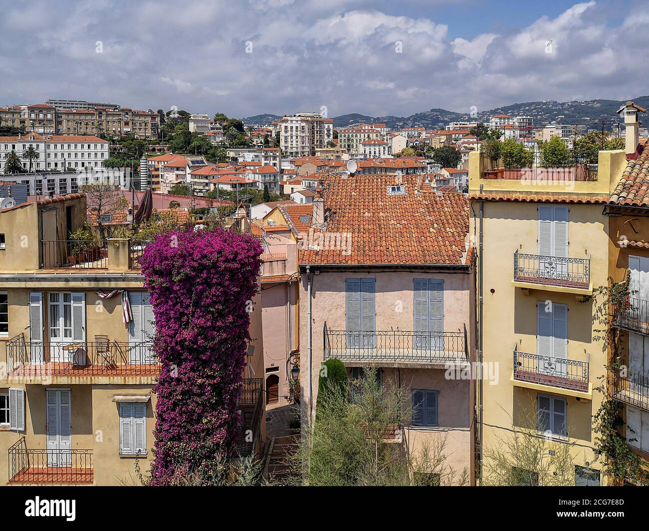 Vue sur la ville de Cannes avec ses vieilles maisons traditionnelles aux toits carrelés de rouge, stores en bois, balcons ouverts, pots de fleurs aux plantes vertes. Banque D'Images