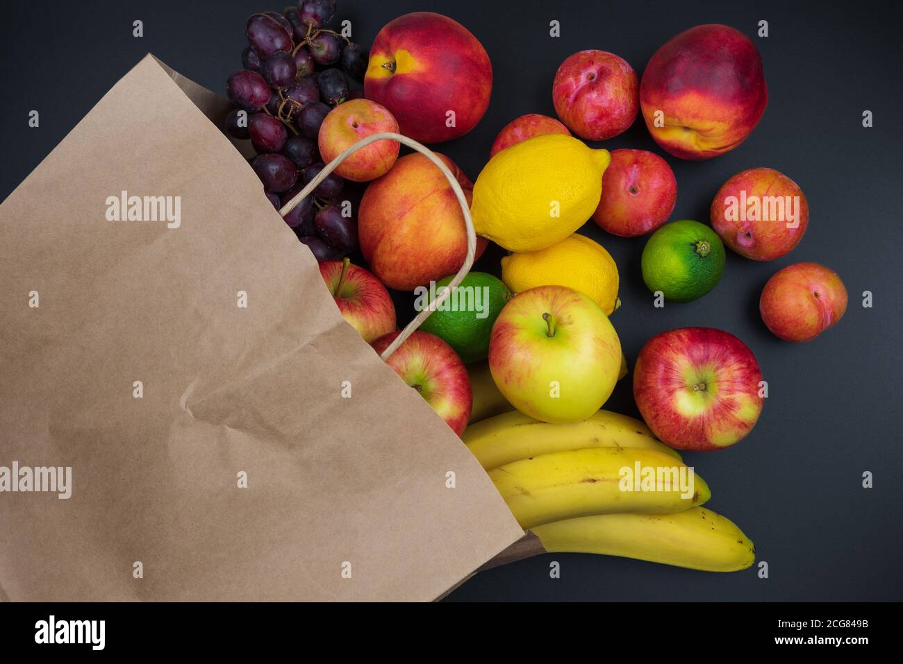 différents fruits frais biologiques dans le papier shopping sur fond de table noire, concept de saine alimentation Banque D'Images