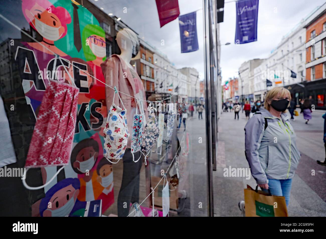 Une femme passe devant un magasin vendant des masques sur Grafton Street à Dublin. L'incapacité du gouvernement à communiquer correctement son message de santé publique Covid-19 a été décrit comme un « abus de pouvoir ». Banque D'Images