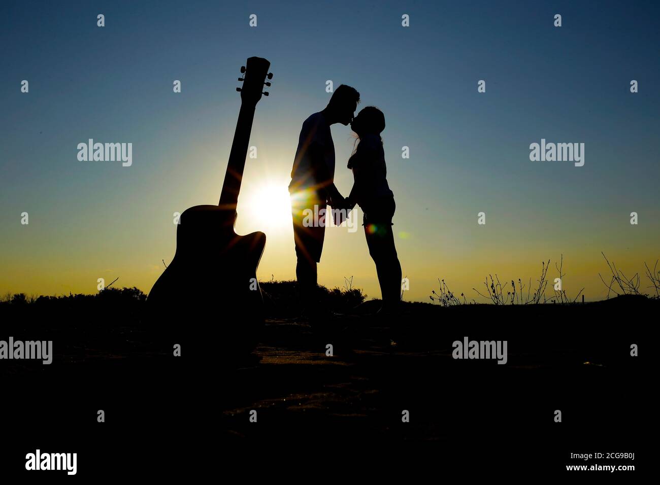 Une jeune famille heureuse et forte en lune de miel. Silhouettes de jeunes mariés sur le fond du ciel du coucher du soleil et de la mer au soleil pendant que W Banque D'Images