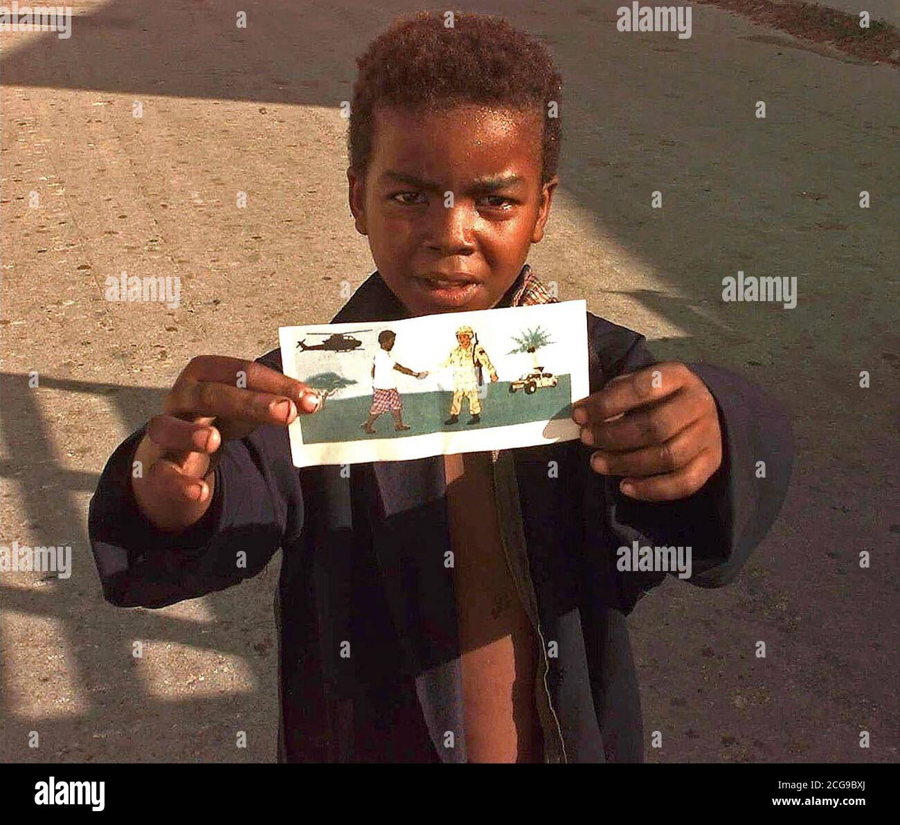 1993 - Un jeune garçon somalien à tenir l'une des brochures d'OPSPSY jusqu'à l'appareil photo. Le dépliant est un dessin à la main un Somalien homme serrant la main d'un membre des Forces canadiennes. L'établissement transmet à la population somalienne qui essayent d'aider à mettre fin à leur souffrance et n'est ici que leurs amis. Banque D'Images