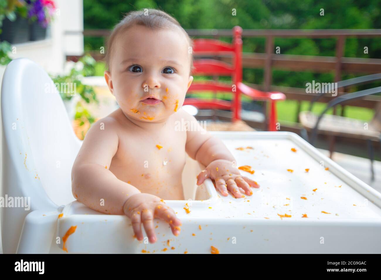 Drôle adorable et sale petite fille de bébé de 6 mois mange en s'asseyant  dans la chaise de bébé Photo Stock - Alamy