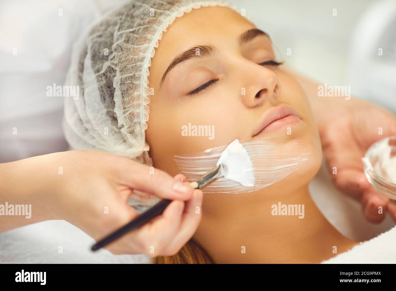 L'esthéticienne fait un masque de beauté à la jeune fille dans la clinique de cosmétologie. Soin du visage Banque D'Images