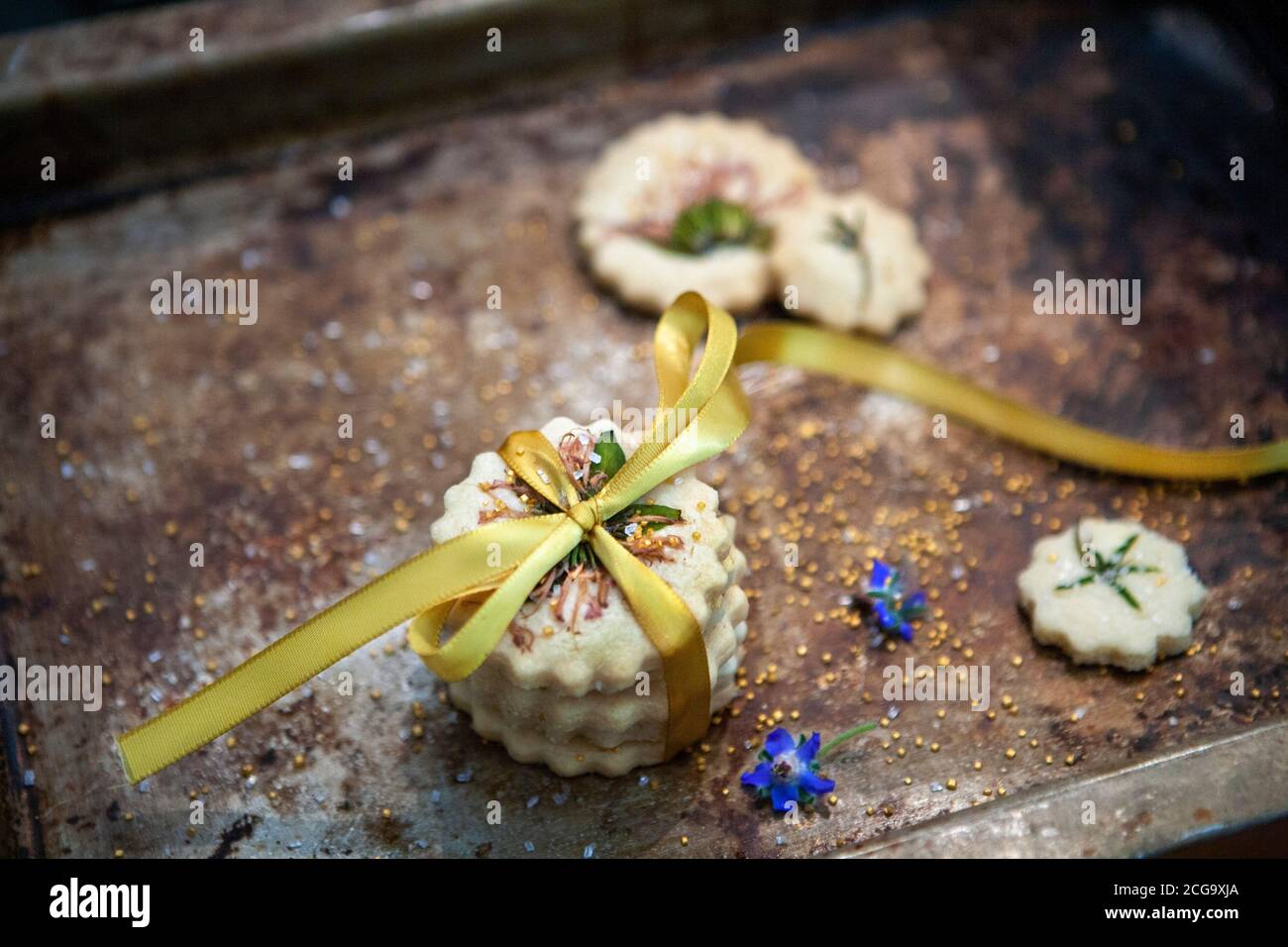 Petite pile de biscuits sablés avec noeud papillon, fleurs comestibles et sucre doré, vue en grand angle Banque D'Images
