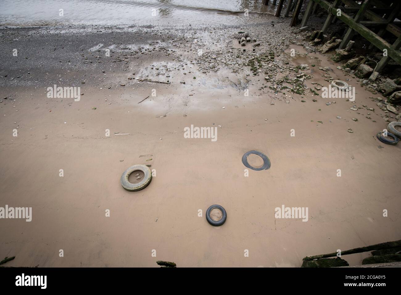 Vieux pneus dans le sable sur l'estran de la Tamise à Greenwich, Londres Banque D'Images