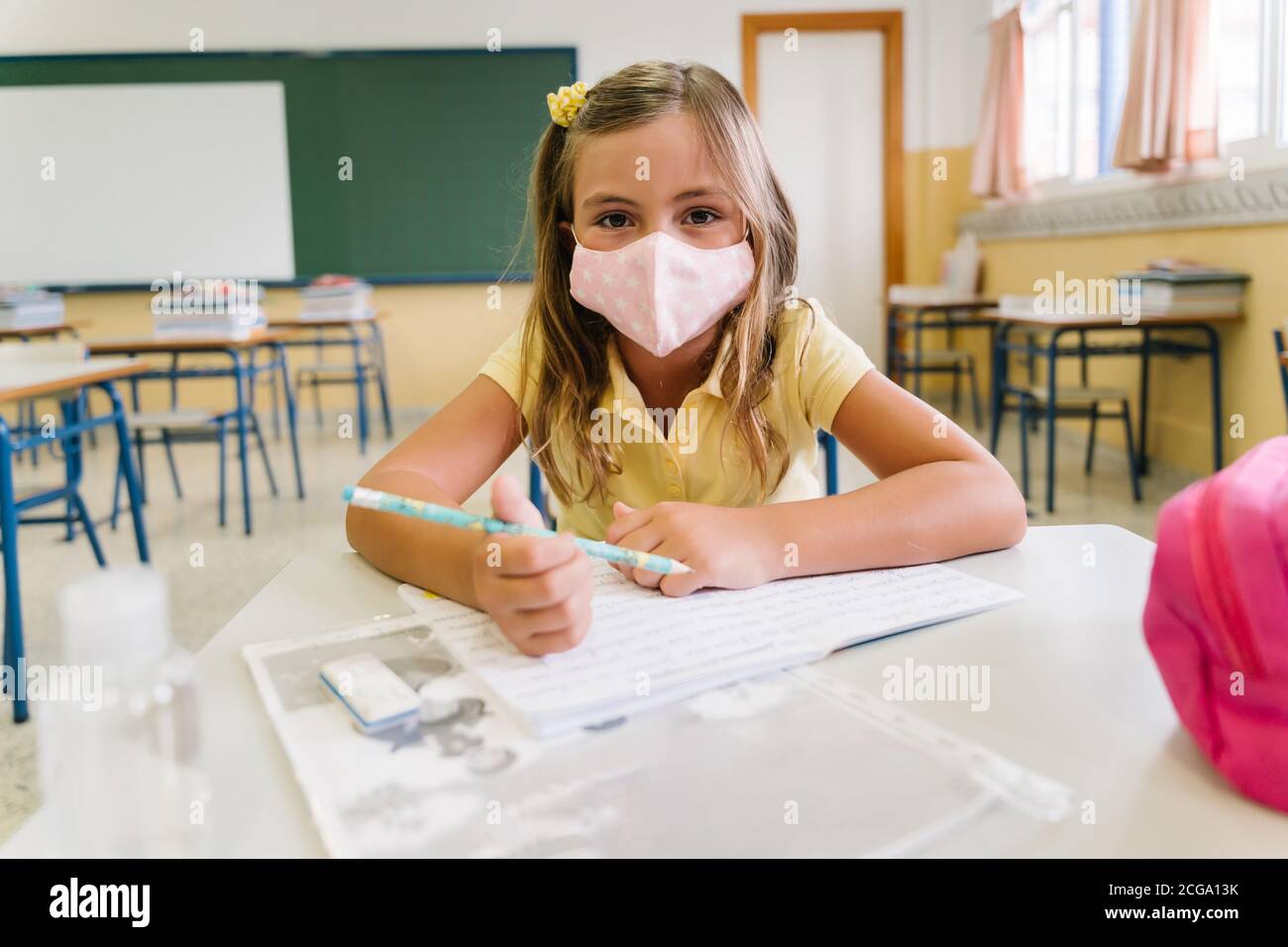 fille assise à sa chaise dans la salle de classe portant un masque. pendant une pandémie de covid Banque D'Images