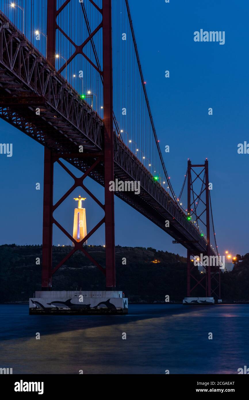 Belle vue sur le pont 25 de Abril au-dessus de la rivière Tejo et la statue de Cristo Rei en début de nuit, centre de Lisbonne, Portugal Banque D'Images