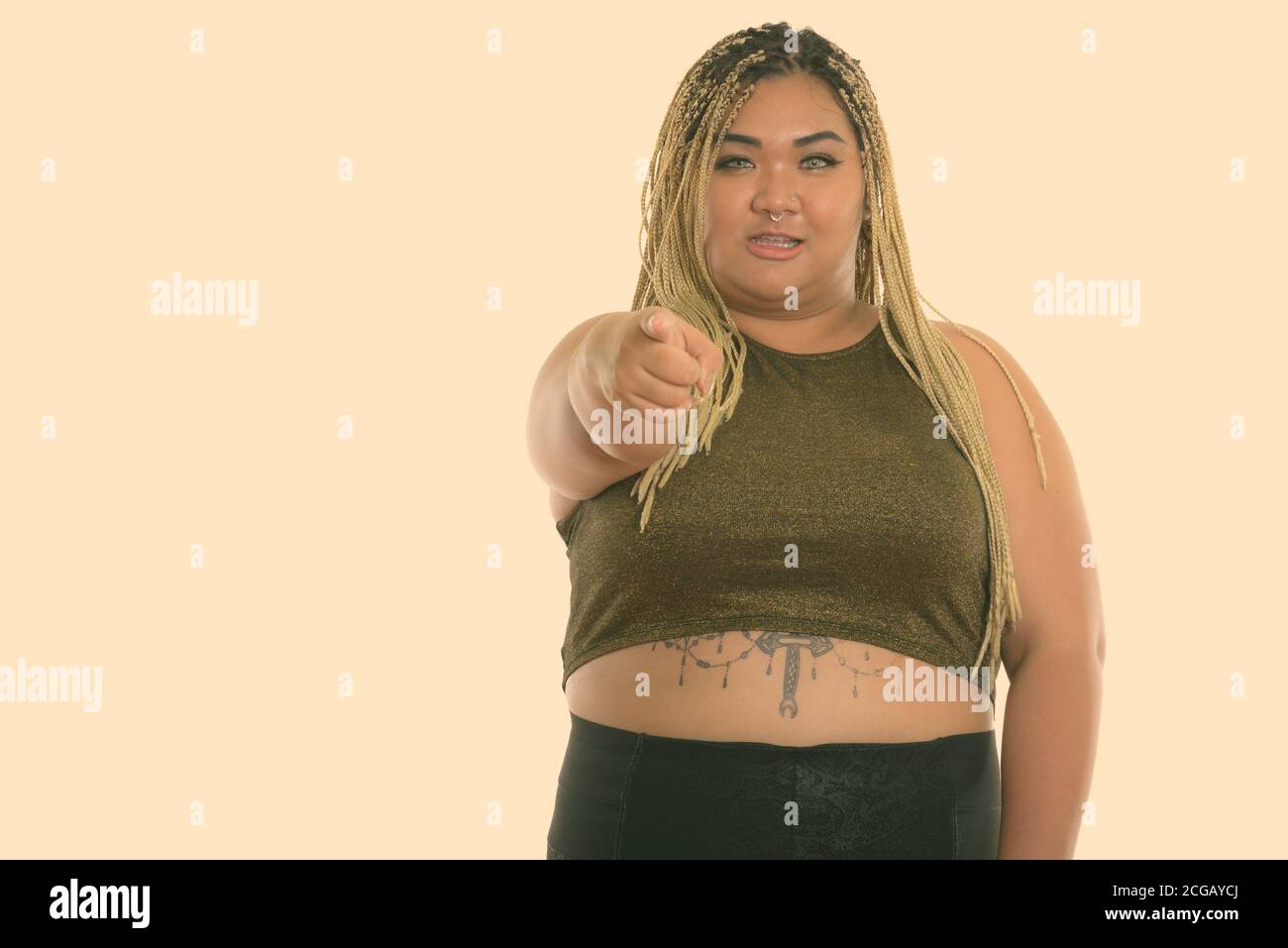 Studio de photo de jeune femme asiatique bonne graisse souriant pendant pointant vers la caméra Banque D'Images