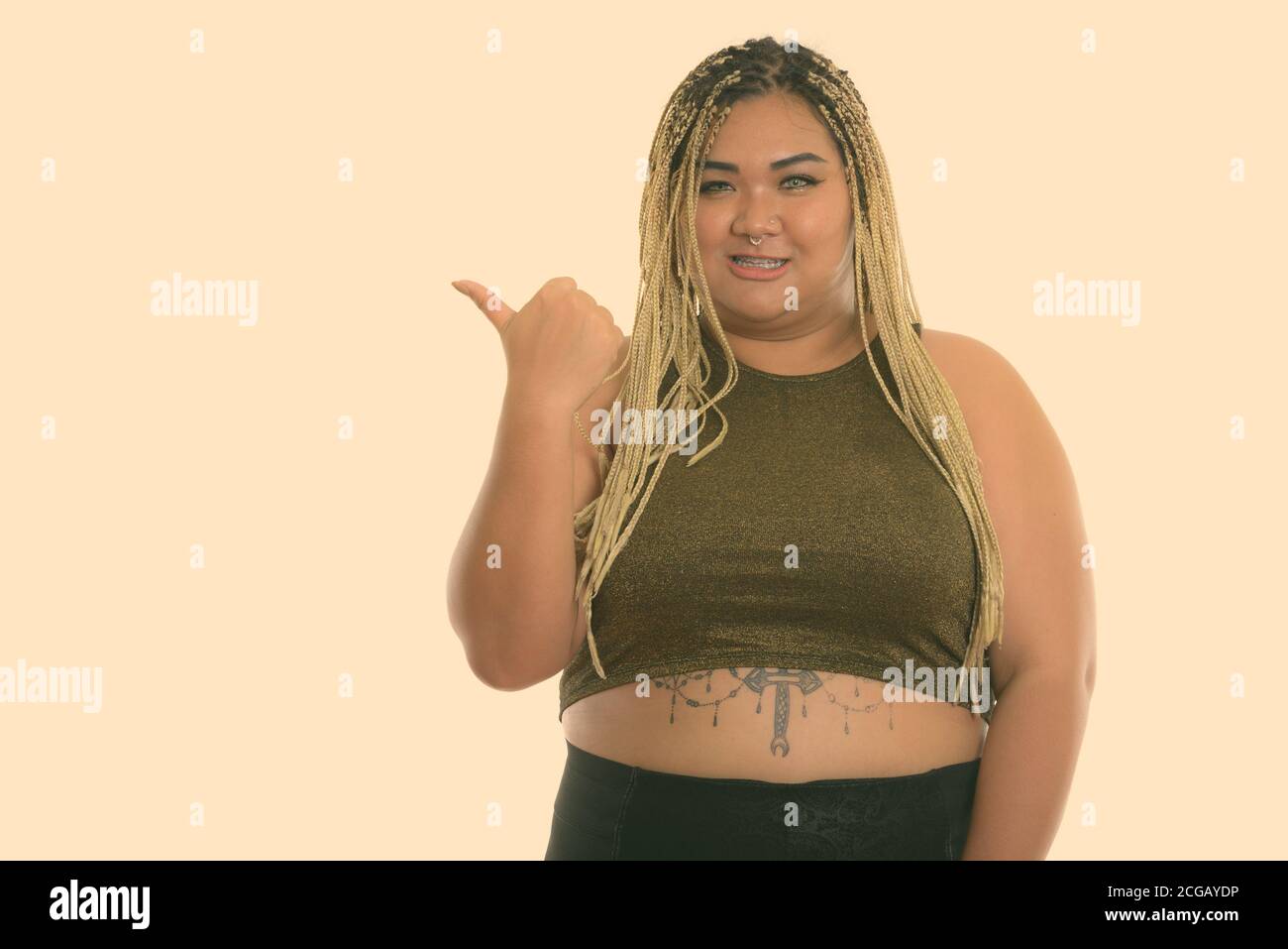 Studio shot of young woman smiling happy fat en pointant sur side Banque D'Images
