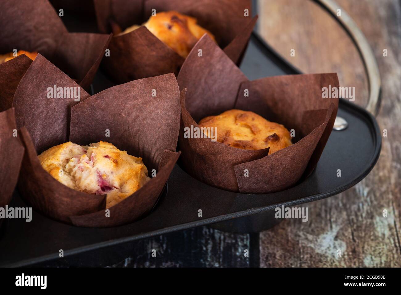 Muffins à l'orange aux canneberges fraîchement cuits faits maison dans des moules à muffins en papier de tulipe marron. Banque D'Images