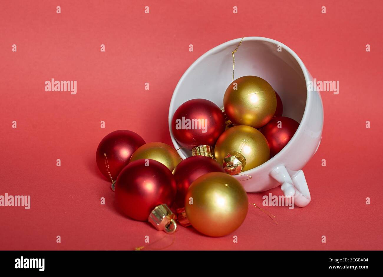 Les boules de Noël rouges et dorées sont en céramique blanche mug sur fond rouge Banque D'Images