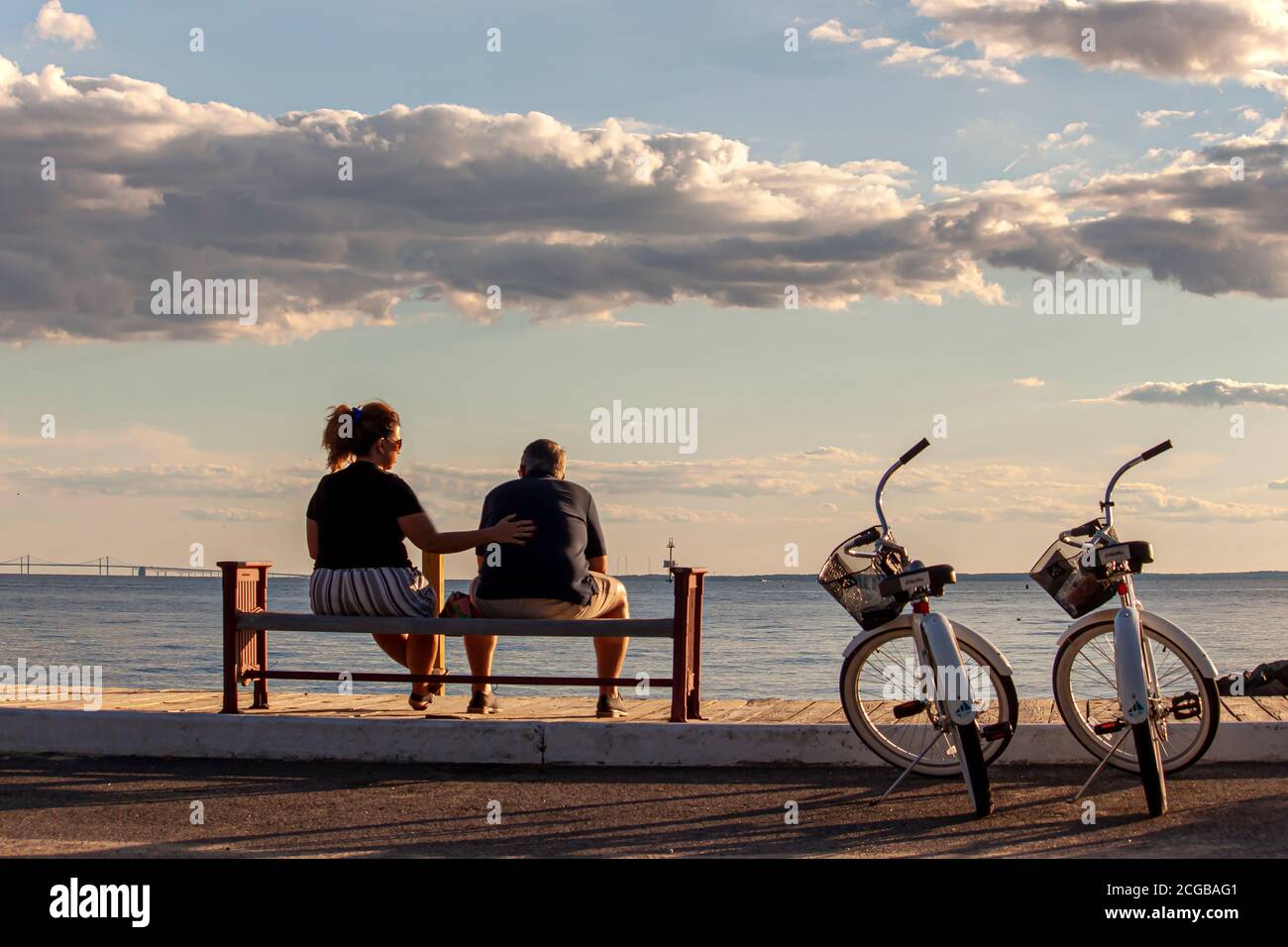 Rock Hall, MD, USA 08/30/2020: Un couple de race blanche d'âge moyen est assis sur un banc près de la plage. Ils ont leurs vélos identiques garés à côté d'eux. Banque D'Images