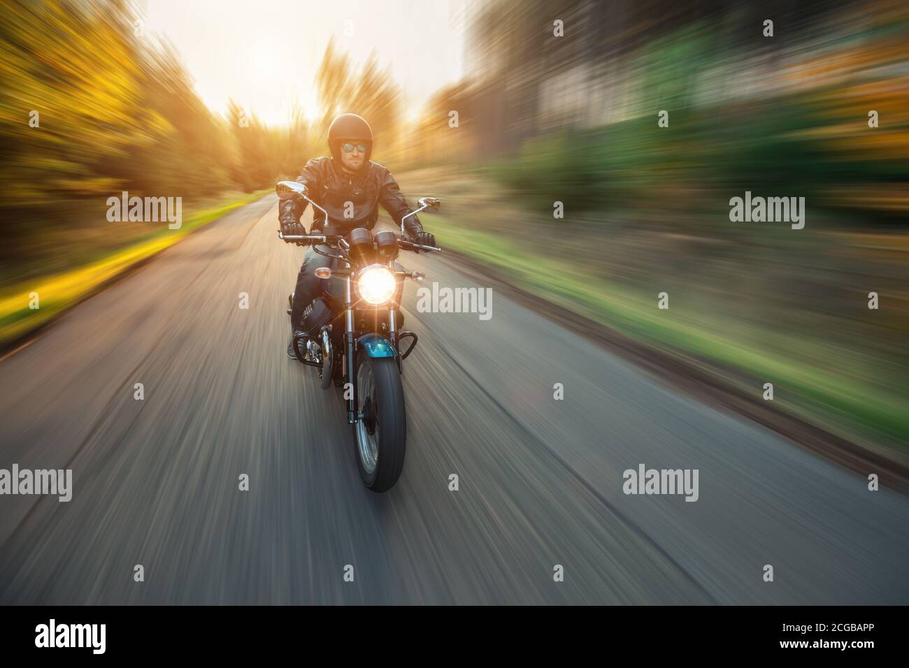 Conducteur de moto roulant dans un paysage forestier avec effet de mouvement flou de l'arrière-plan environnant. Banque D'Images