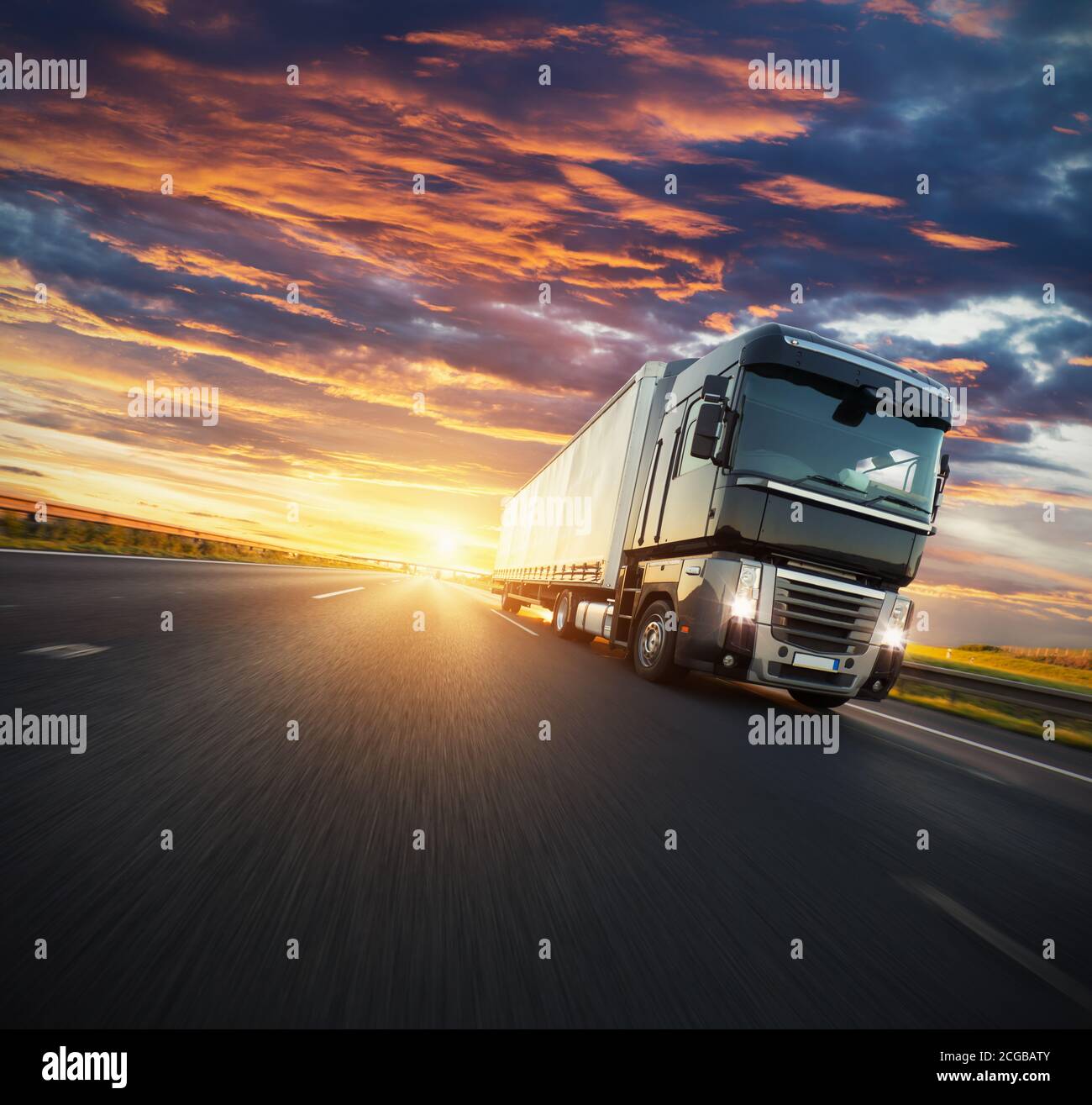 Camion européen sur autoroute avec lumière spectaculaire au coucher du soleil. Thème du transport de marchandises et de l'approvisionnement. Banque D'Images