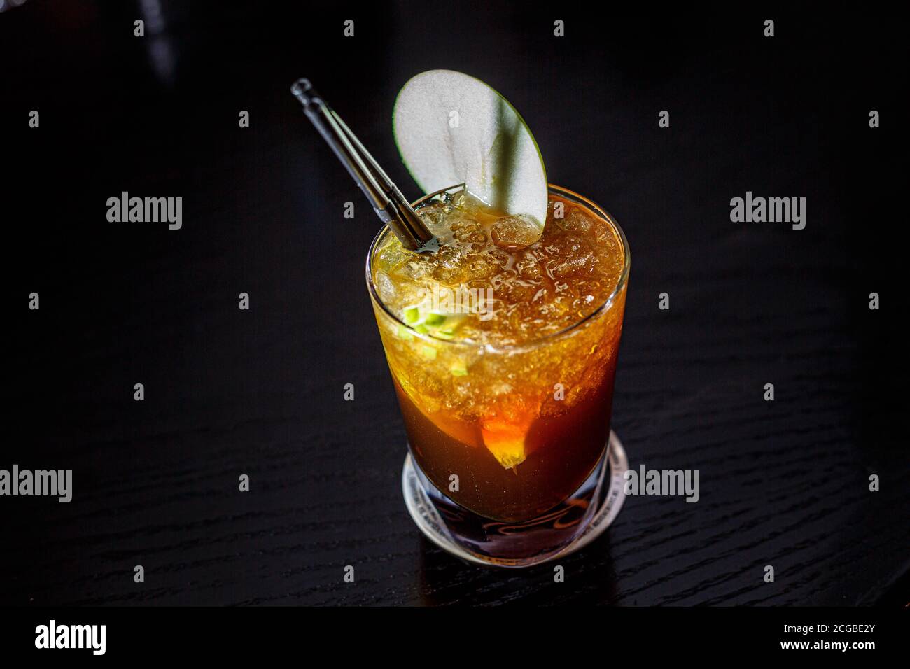 Un cocktail avec whisky, cognac ou Cola dans un verre de High ball est sur le comptoir d'un bar sombre. Banque D'Images