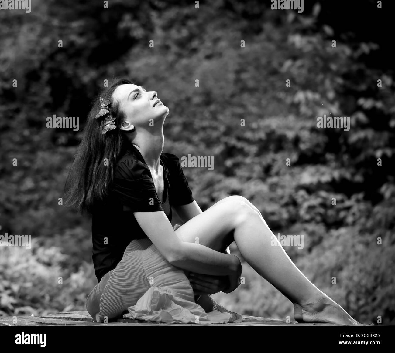 Jeune femme brunet assise à l'extérieur sur un banc en bois Banque D'Images